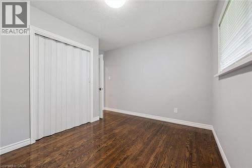 Hardwood flooring, light gray walls, white trim, and a white accordion door closet - 49 East Street, Cambridge, ON - Indoor Photo Showing Other Room