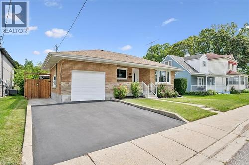 Brick exterior with an attached garage, paved driveway, and manicured front lawn - 49 East Street, Cambridge, ON - Outdoor With Facade