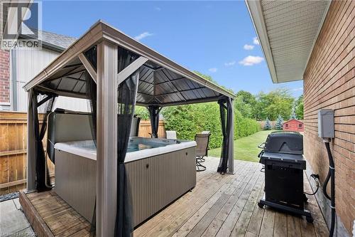 Wood deck featuring a covered hot tub, brick exterior, and a spacious lawn - 49 East Street, Cambridge, ON - Outdoor With Deck Patio Veranda With Exterior