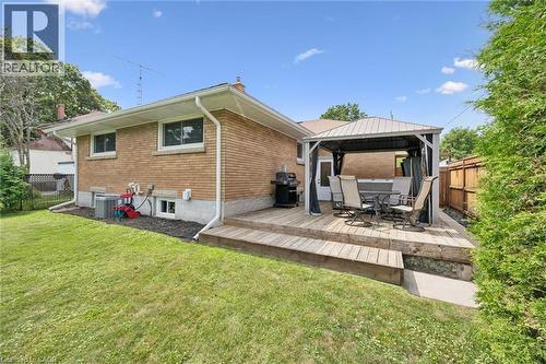Brick exterior with white window frames and gutters, featuring an elevated wood deck and a manicured lawn - 49 East Street, Cambridge, ON - Outdoor With Deck Patio Veranda With Exterior