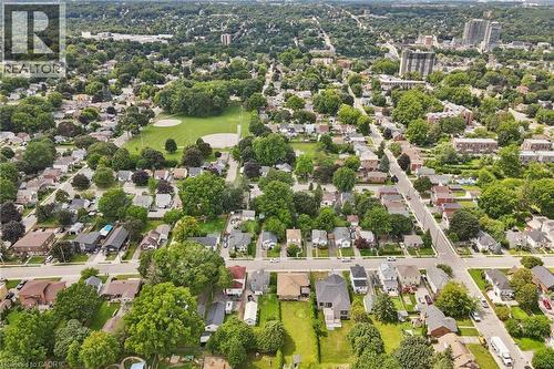 Aerial perspective of a verdant residential area with mature tree canopies, featuring a large green space with a sports field, multiple residential streets, and distant urban structures - 49 East Street, Cambridge, ON - Outdoor With View