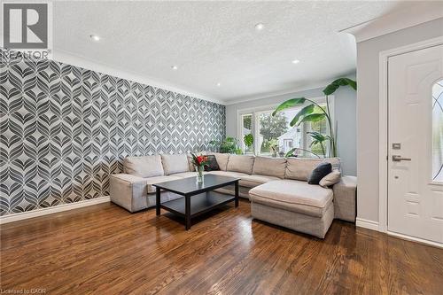 Hardwood flooring, recessed lighting, decorative accent wall, large window with natural light, and a paneled entry door - 49 East Street, Cambridge, ON - Indoor Photo Showing Living Room