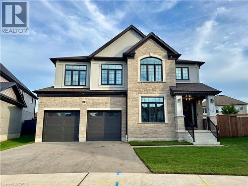 Stone and stucco exterior with dark trim accents, a prominent arched window, two-car garage, and covered front entry - 923 Eaglecrest Court, Kitchener, ON - Outdoor With Facade