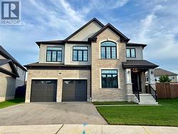 Stone and stucco exterior with dark trim accents, a prominent arched window, two-car garage, and covered front entry - 