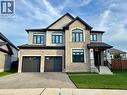 Stone and stucco exterior with dark trim accents, a prominent arched window, two-car garage, and covered front entry - 923 Eaglecrest Court, Kitchener, ON  - Outdoor With Facade 