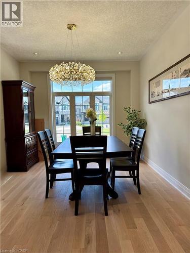 Bright interior space featuring light wood-finish flooring, a contemporary chandelier, recessed ceiling lighting, and crown molding - 923 Eaglecrest Court, Kitchener, ON - Indoor Photo Showing Dining Room