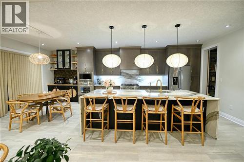 Spacious kitchen featuring an expansive central island with seating, integrated sink, and modern pendant lighting - 923 Eaglecrest Court, Kitchener, ON - Indoor Photo Showing Dining Room