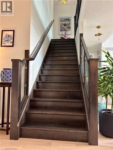 Hardwood staircase with glass panel railing and dark wood newel posts - 923 Eaglecrest Court, Kitchener, ON - Indoor Photo Showing Other Room