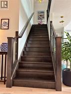 Hardwood staircase with glass panel railing and dark wood newel posts - 