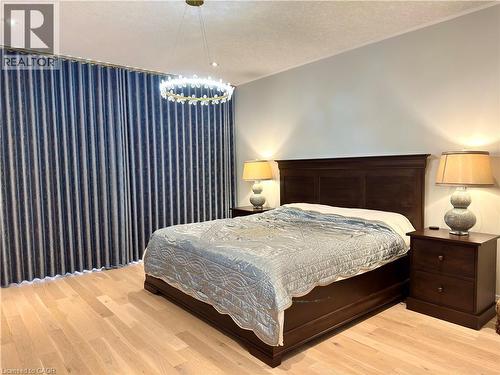 Wood-finish flooring, full-height window treatments, and a decorative chandelier - 923 Eaglecrest Court, Kitchener, ON - Indoor Photo Showing Bedroom