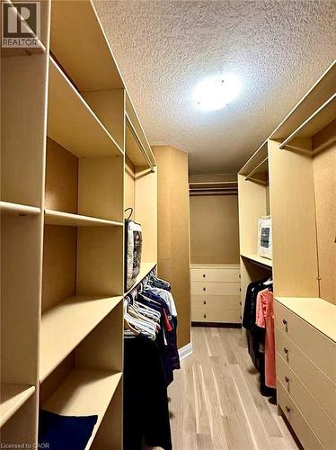 Walk-through closet featuring built-in shelving, hanging rods, integrated drawer storage, and wood-finish flooring - 923 Eaglecrest Court, Kitchener, ON - Indoor With Storage