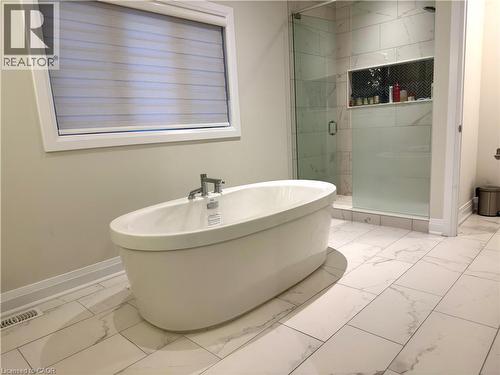 Freestanding bathtub with chrome fixtures, large format tile flooring, and a glass-enclosed shower with a tiled niche - 923 Eaglecrest Court, Kitchener, ON - Indoor Photo Showing Bathroom