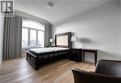 Arched window with extensive glazing, light wood-finish flooring, and neutral wall tones - 923 Eaglecrest Court, Kitchener, ON - Indoor Photo Showing Bedroom