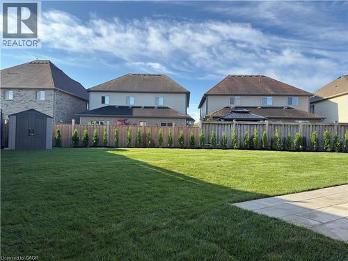 Expansive green lawn, paver patio, wood privacy fence, and manicured evergreen plantings - 923 Eaglecrest Court, Kitchener, ON - Outdoor With Deck Patio Veranda