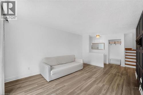 Wood-finish flooring, white wall finishes, built-in storage niche, wood stair treads, and a semi-flush mount ceiling light - 27 Gretna Court, Hamilton, ON - Indoor Photo Showing Other Room