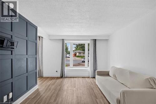 Wood-finish flooring throughout, bright white walls, and a large bay window - 27 Gretna Court, Hamilton, ON - Indoor
