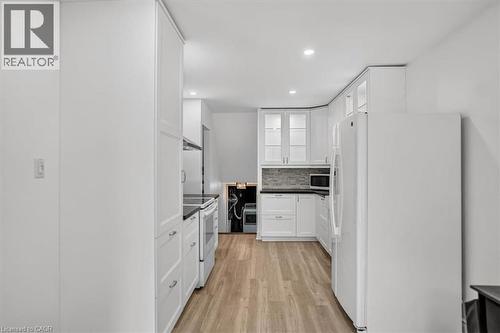 Kitchen featuring white cabinetry, black countertops, stainless steel appliances, and wood-finish flooring - 27 Gretna Court, Hamilton, ON - Indoor Photo Showing Kitchen