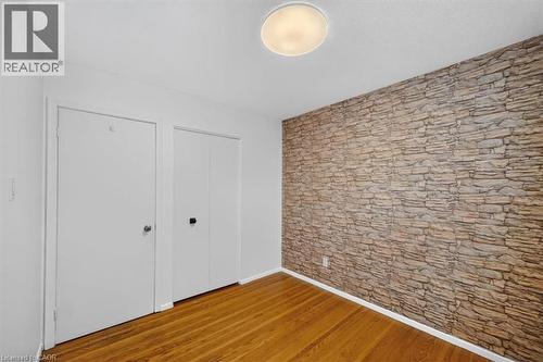 Hardwood flooring and a stone-effect accent wall - 27 Gretna Court, Hamilton, ON - Indoor Photo Showing Other Room