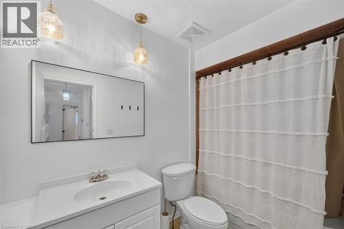Vanity with integrated sink and chrome-finish faucet, rectangular framed mirror, and two pendant light fixtures - 27 Gretna Court, Hamilton, ON - Indoor Photo Showing Bathroom