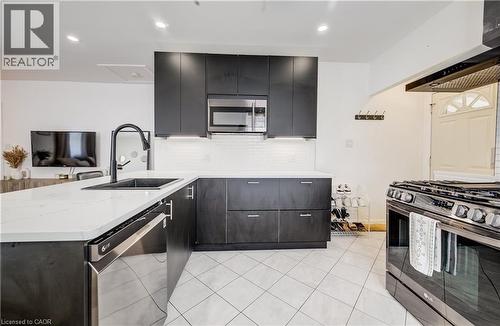 Kitchen featuring dark wood-finish cabinetry, light-toned countertops, a stainless steel microwave, a black sink with a black faucet, and white subway tile backsplash - 34 St Clair Avenue, Kitchener, ON - Indoor Photo Showing Kitchen With Upgraded Kitchen