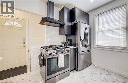 Stainless steel appliances, white subway tile backsplash, dark cabinetry, and white tile flooring - 34 St Clair Avenue, Kitchener, ON - Indoor Photo Showing Kitchen