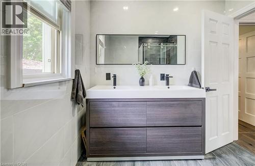 Dual sink vanity with wood-finish cabinetry, matte black fixtures, and a framed mirror - 34 St Clair Avenue, Kitchener, ON - Indoor Photo Showing Bathroom