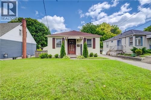 Single-story residence featuring light-colored siding, a dark-toned roof, and a front entrance with a covered overhang - 34 St Clair Avenue, Kitchener, ON - Outdoor