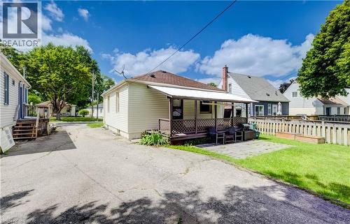 Rear exterior featuring light-colored siding, a covered porch with lattice railing, a paved patio area, and a grass lawn - 34 St Clair Avenue, Kitchener, ON - Outdoor With Deck Patio Veranda