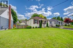 Expansive lawn with mature trees, a covered front porch, and a paved walkway - 