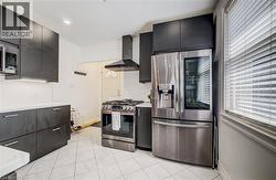 Modern kitchen featuring dark cabinetry, stainless steel appliances, white subway tile backsplash, and white countertops - 