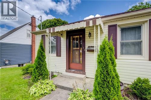 Cream-colored siding, brown window shutters, and a front entry door with decorative glass - 34 St Clair Avenue, Kitchener, ON - Outdoor With Exterior