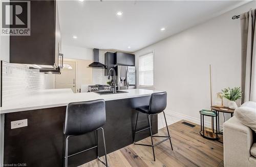 Contemporary kitchen featuring dark cabinetry, white countertops, and a white subway tile backsplash - 34 St Clair Avenue, Kitchener, ON - Indoor Photo Showing Kitchen
