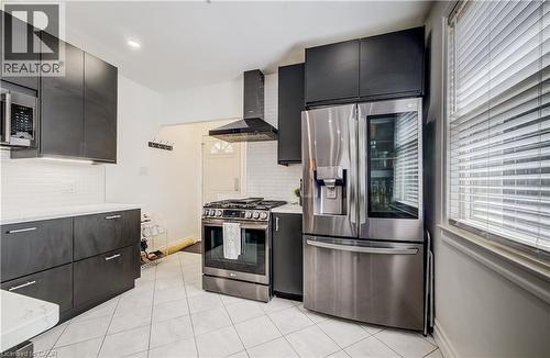 Modern kitchen featuring dark cabinetry, stainless steel appliances, white subway tile backsplash, and white countertops - 34 St Clair Avenue, Kitchener, ON - Indoor Photo Showing Kitchen