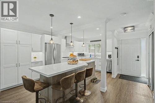 Modern kitchen featuring white shaker cabinetry, stainless steel appliances, a center island with counter seating, quartz countertops, and wood-finish flooring - 2050 Upper Middle Road Unit# 164, Burlington, ON - Indoor Photo Showing Kitchen With Upgraded Kitchen