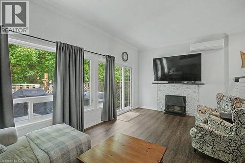 Living space with wood-finish flooring, a white-painted brick fireplace, and integrated heating/cooling unit - 2050 Upper Middle Road Unit# 164, Burlington, ON - Indoor Photo Showing Living Room With Fireplace