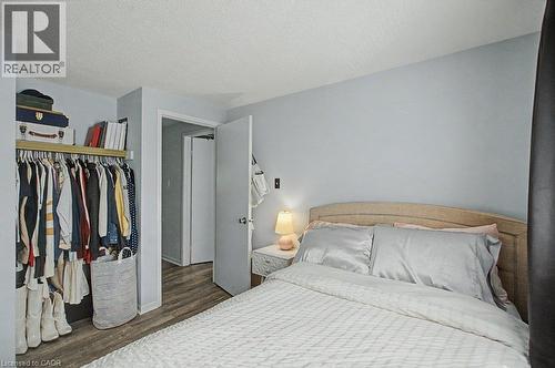 Bedroom featuring a built-in closet with shelving, wood-finish flooring, and a white interior door - 2050 Upper Middle Road Unit# 164, Burlington, ON - Indoor Photo Showing Bedroom