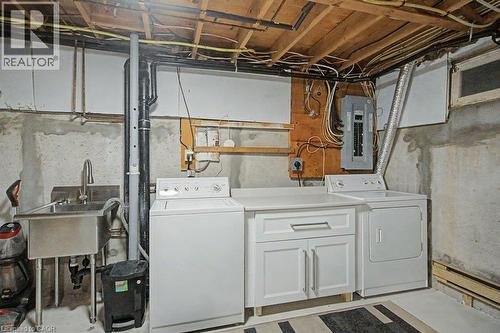 Laundry area featuring a utility sink, a washer, a dryer, and built-in white cabinetry with a countertop - 2050 Upper Middle Road Unit# 164, Burlington, ON - Indoor Photo Showing Laundry Room