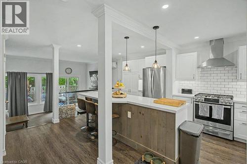 Kitchen featuring wood-finish flooring, white cabinetry, subway tile backsplash, stainless steel appliances, and a breakfast bar with paneling - 2050 Upper Middle Road Unit# 164, Burlington, ON - Indoor Photo Showing Kitchen With Upgraded Kitchen