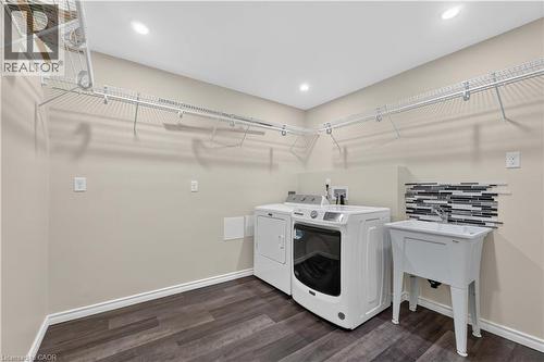 Laundry room featuring wood-finish flooring, recessed lighting, wire shelving, and a utility sink with a tiled backsplash - 66 Summercrest Drive Unit# 3, Hamilton, ON - Indoor Photo Showing Laundry Room