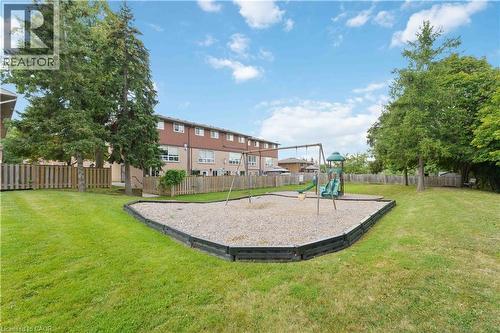 Expansive green space featuring a wood-edged play area with swings and a slide structure - 66 Summercrest Drive Unit# 3, Hamilton, ON - Outdoor