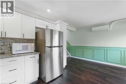 White cabinetry, granite-look countertop, tile backsplash, dark wood-finish flooring, and decorative wainscoting - 66 Summercrest Drive Unit# 3, Hamilton, ON - Indoor Photo Showing Kitchen
