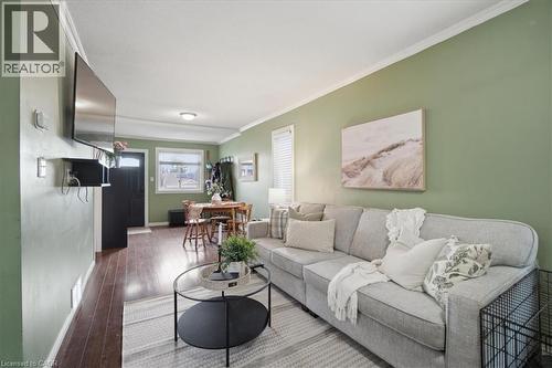 Open-concept living area featuring rich wood-finish flooring, light green walls, and white crown molding - 22 Delena Avenue N, Hamilton, ON - Indoor Photo Showing Other Room