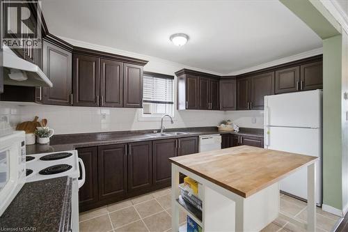 Dark wood-finish cabinetry, tile flooring, white tile backsplash, and a butcher block island - 22 Delena Avenue N, Hamilton, ON - Indoor Photo Showing Bathroom