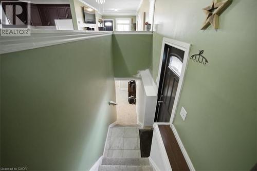 Staircase featuring carpeted treads, tiled landing, and a handrail - 22 Delena Avenue N, Hamilton, ON - Indoor Photo Showing Kitchen With Double Sink