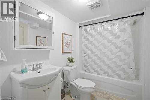 White vanity with an integrated sink and chrome faucet, white medicine cabinet, and a white bathtub with a shower curtain - 22 Delena Avenue N, Hamilton, ON - Indoor Photo Showing Bathroom