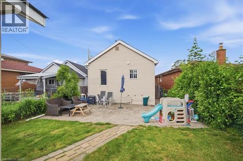 Expansive backyard featuring a manicured lawn, a large concrete patio, and a paver stone pathway - 22 Delena Avenue N, Hamilton, ON - Outdoor With Deck Patio Veranda