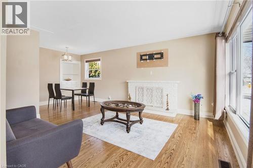 Hardwood flooring, white brick fireplace, built-in shelving, large windows with natural light, and a dedicated dining space - 185 Burlington Street, London, ON - Indoor Photo Showing Living Room