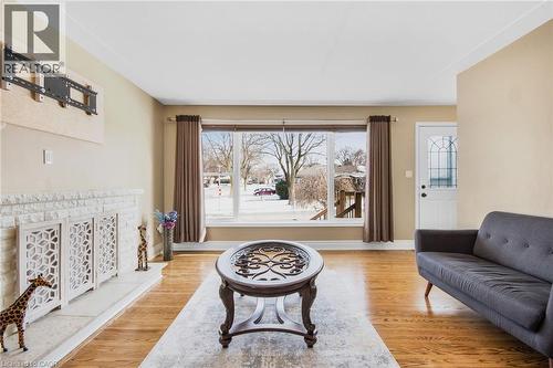 Hardwood flooring, white fireplace with decorative screens, large window with outdoor visibility, white paneled door with leaded glass, white crown molding - 185 Burlington Street, London, ON - Indoor Photo Showing Living Room