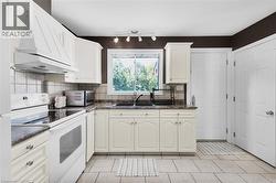Kitchen featuring white cabinetry, gray stone-finish countertops, and a tile backsplash - 