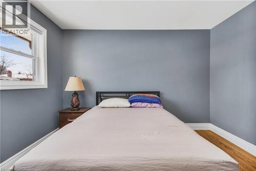 Wood-finish flooring with white baseboards, a white window frame, and neutral wall paint - 185 Burlington Street, London, ON - Indoor Photo Showing Bedroom